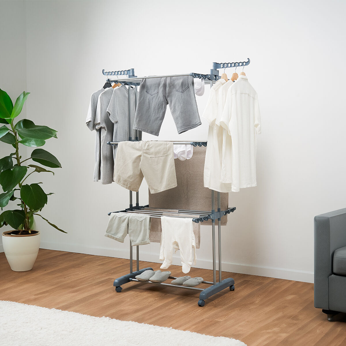 Tendedero vertical plegable con ruedas y tres niveles con ropa tendida dentro de un piso