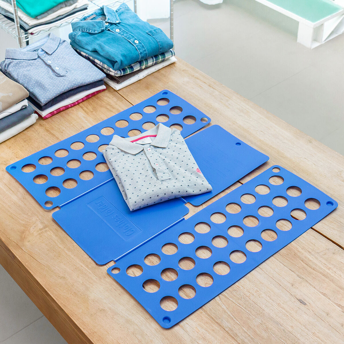 Doblador de ropa InnovaGoods azul con una camiseta a medio doblar